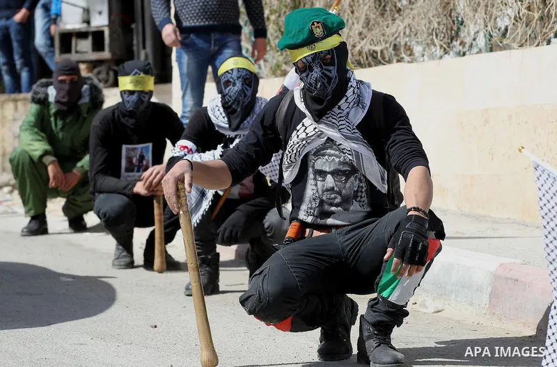 Masked Palestinians holds the pictures of Palestinian teenager Qusai Al-Amour, a 17-year-old who was shot dead, during a demonstration in the West Bank village of Tuqua, near Bethlehem, 26 February 2017. Emoor, a member...