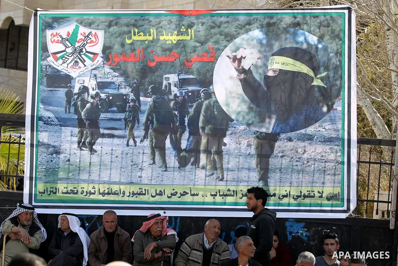 Masked Palestinians holds the pictures of Palestinian teenager Qusai Al-Amour, a 17-year-old who was shot dead, during a demonstration in the West Bank village of Tuqua, near Bethlehem, 26 February 2017. Emoor, a member...
