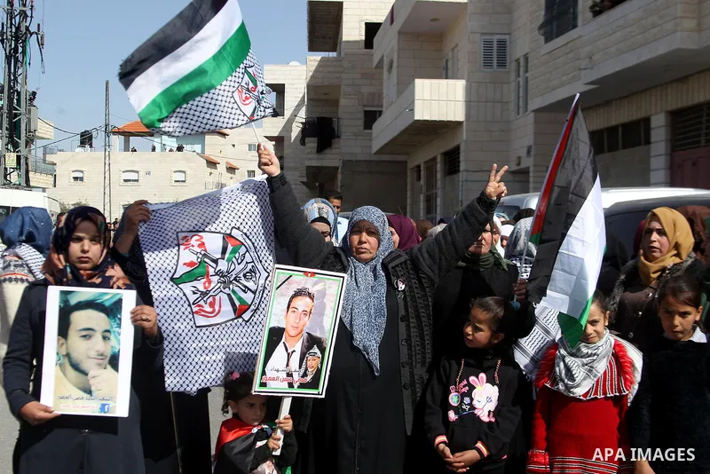 Masked Palestinians holds the pictures of Palestinian teenager Qusai Al-Amour, a 17-year-old who was shot dead, during a demonstration in the West Bank village of Tuqua, near Bethlehem, 26 February 2017. Emoor, a member...