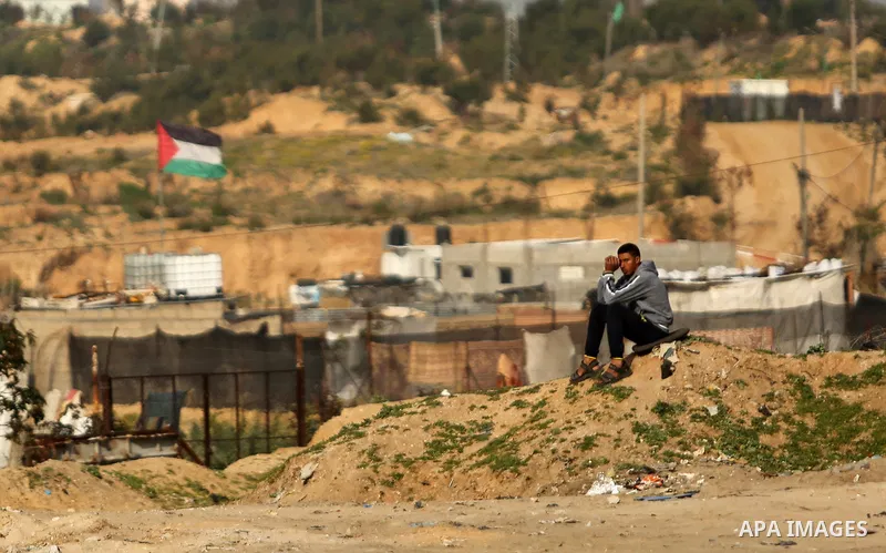 A Palestinian youth sists outside his house in Beit Lahia, near the border with Israel, in the northern Gaza Strip, on February 27, 2017. Photo by Ashraf Amra