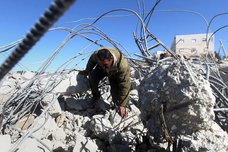 A Palestinian man looks for his belongings amongst the rubble of her house after it was demolished by the Israeli army as it did not have an Israeli-issued construction permit, in the West Bank city of Hebron March 6, 20...