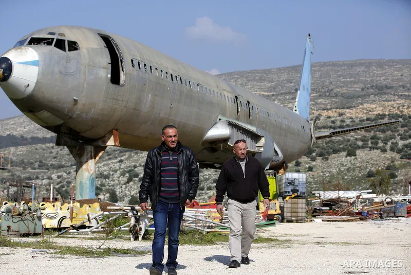 Palestinian taxi vans walk near a retired Boeing airplane once belonging to an Israeli airline has standing in an empty ground in the west bank city of Nablus, on March 7, 2017. Photo by Wisam Hashlamoun