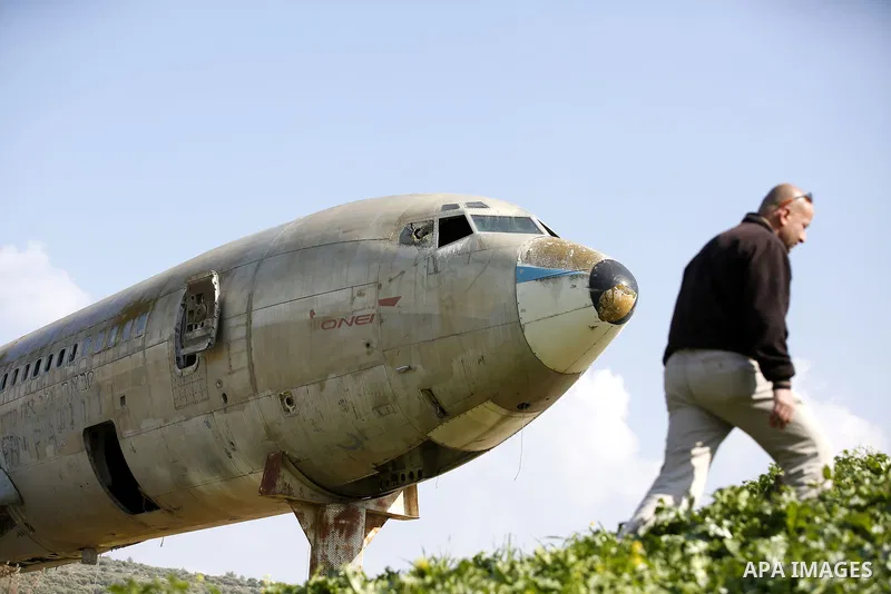 A Palestinian taxi van walks near a retired Boeing airplane once belonging to an Israeli airline has standing in an empty ground in the west bank city of Nablus, on March 7, 2017. Photo by Wisam Hashlamoun