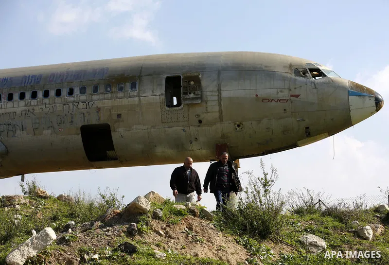 Palestinian taxi vans walk near a retired Boeing airplane once belonging to an Israeli airline has standing in an empty ground in the west bank city of Nablus, on March 7, 2017. Photo by Wisam Hashlamoun