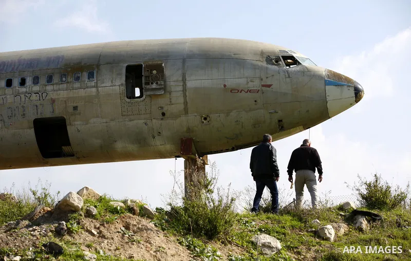 Palestinian taxi vans walk near a retired Boeing airplane once belonging to an Israeli airline has standing in an empty ground in the west bank city of Nablus, on March 7, 2017. Photo by Wisam Hashlamoun