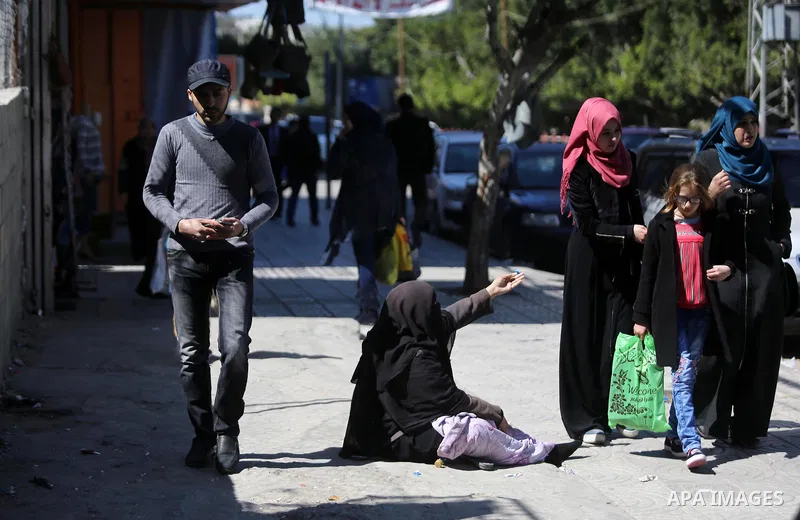 A Palestinian woman begs for handouts at street on International Women's Day on March 08, 2017. Photo by Ashraf Amra