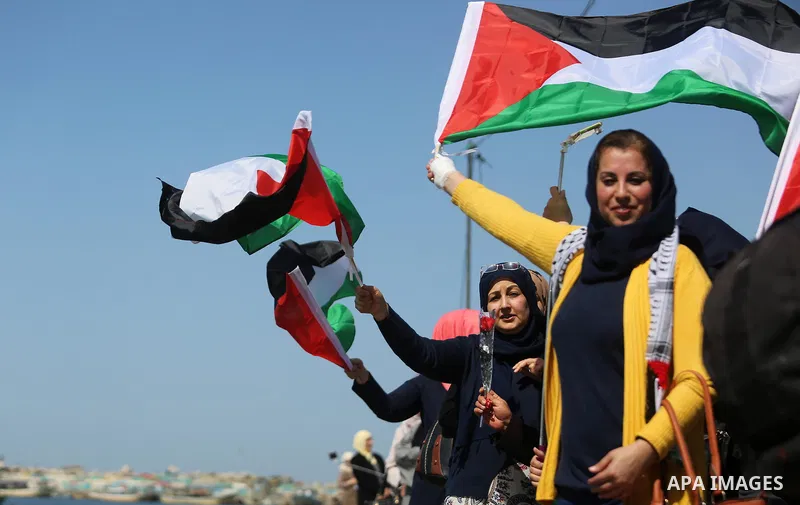 Palestinian women throw letters and flowers during a demonstration marking International Women's Day, in Gaza City on March 9, 2017. Photo by Ashraf Amra