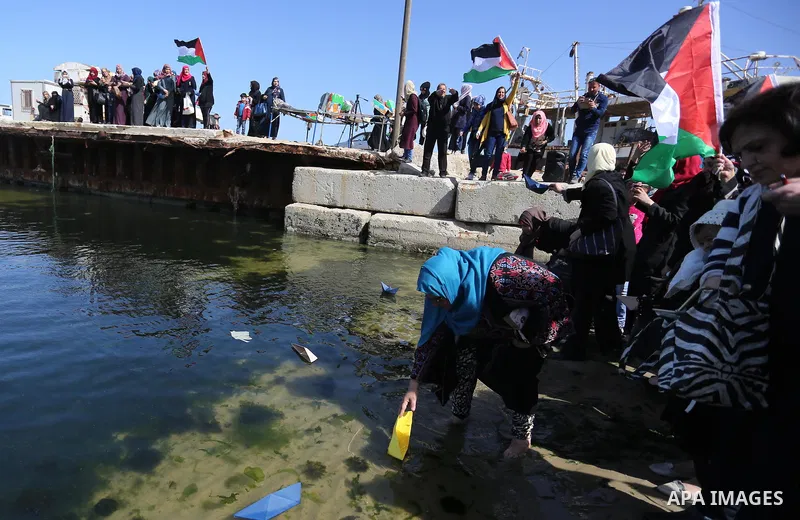 Palestinian women throw letters and flowers during a demonstration marking International Women's Day, in Gaza City on March 9, 2017. Photo by Ashraf Amra
