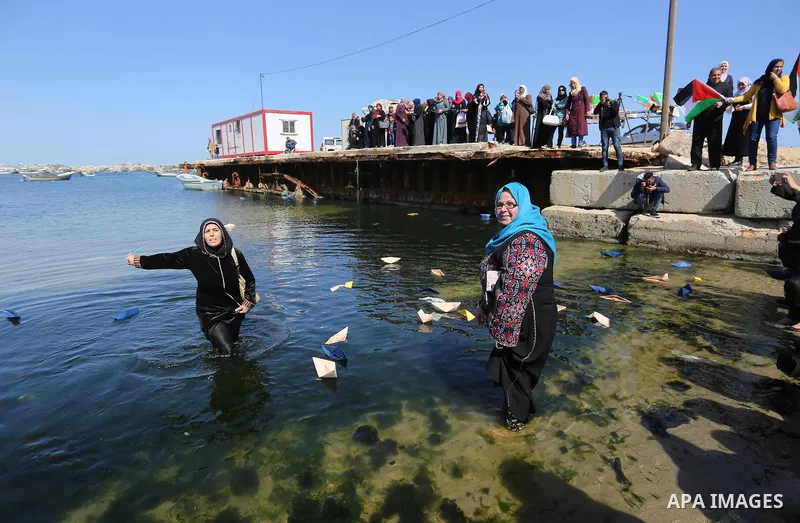 Palestinian women throw letters and flowers during a demonstration marking International Women's Day, in Gaza City on March 9, 2017. Photo by Ashraf Amra