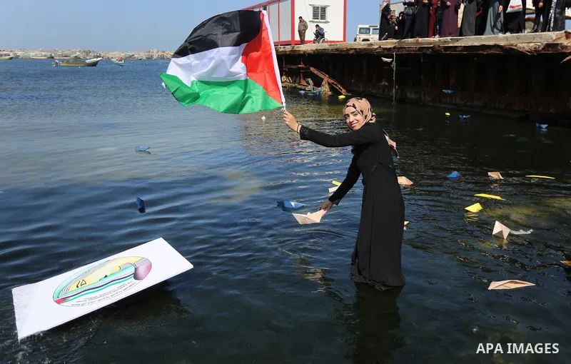 Palestinian women throw letters and flowers during a demonstration marking International Women's Day, in Gaza City on March 9, 2017. Photo by Ashraf Amra