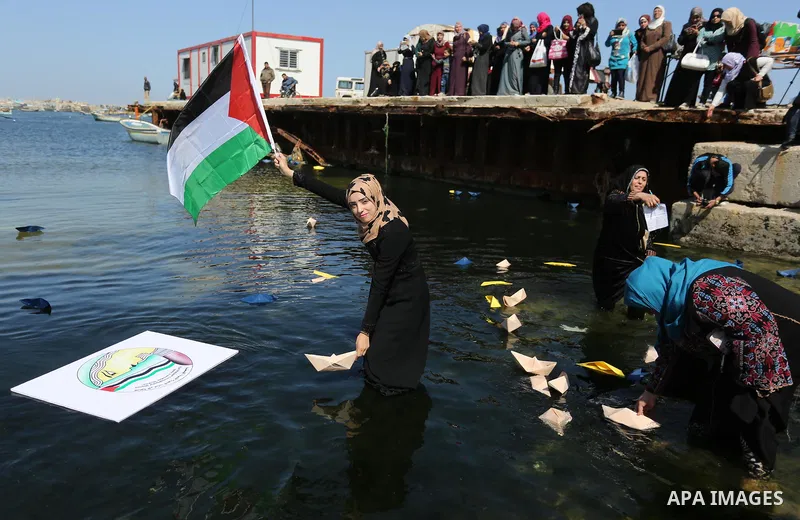 Palestinian women throw letters and flowers during a demonstration marking International Women's Day, in Gaza City on March 9, 2017. Photo by Ashraf Amra