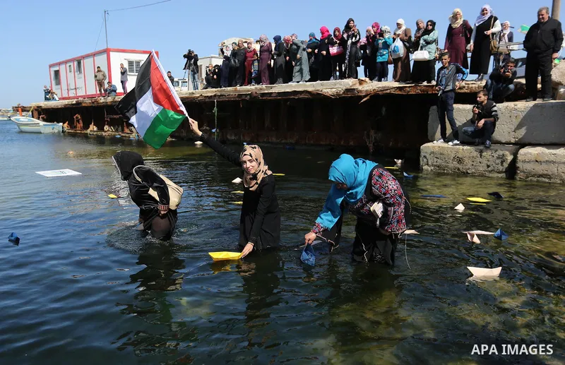 Palestinian women throw letters and flowers during a demonstration marking International Women's Day, in Gaza City on March 9, 2017. Photo by Ashraf Amra
