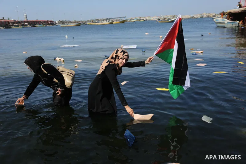 Palestinian women throw letters and flowers during a demonstration marking International Women's Day, in Gaza City on March 9, 2017. Photo by Ashraf Amra