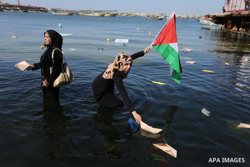 Palestinian women throw letters and flowers during a demonstration marking International Women's Day, in Gaza City on March 9, 2017. Photo by Ashraf Amra