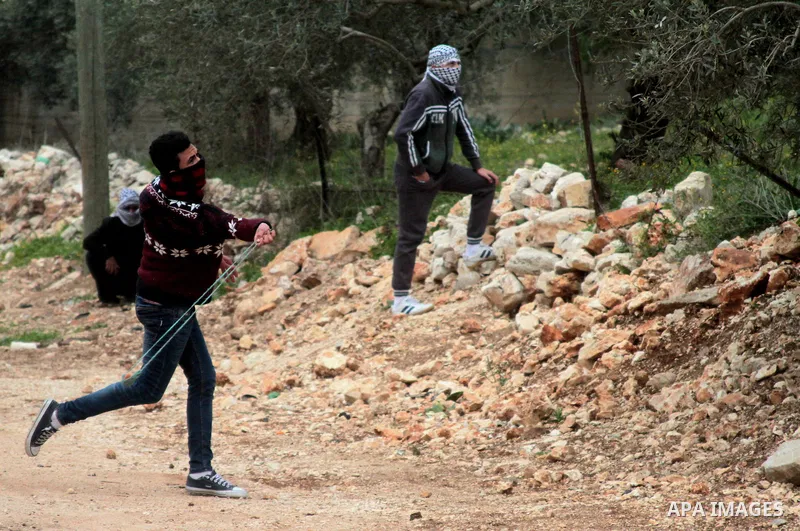 A Palestinian protester uses a slingshot to hurl stones at Israeli security forces during clashes following a weekly demonstration against the expropriation of Palestinian land by Israel in the village of Kfar Qaddum, ne...