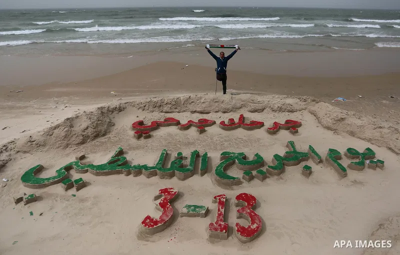 A Palestinian artist Mohammed Totah with amputated leg poses for a picture behind a sand sculpture to mark the Palestinian Wounded's Day in Gaza City, on March 12, 2017. Photo by Ashraf Amra