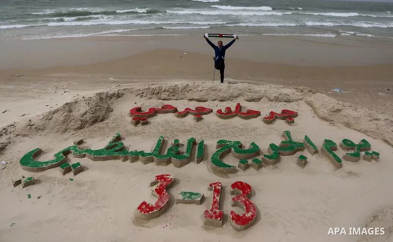 A Palestinian artist Mohammed Totah with amputated leg poses for a picture behind a sand sculpture to mark the Palestinian Wounded's Day in Gaza City, on March 12, 2017. Photo by Ashraf Amra