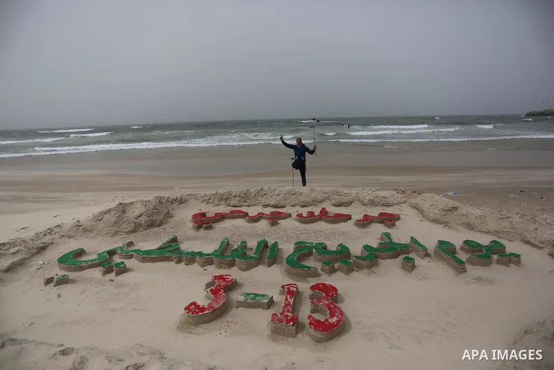 A Palestinian artist Mohammed Totah with amputated leg poses for a picture behind a sand sculpture to mark the Palestinian Wounded's Day in Gaza City, on March 12, 2017. Photo by Ashraf Amra