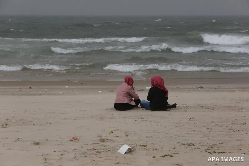 Palestinian girls sit in front of the beach at the Gaza seaport on March 12, 2017. Photo by Ashraf Amra