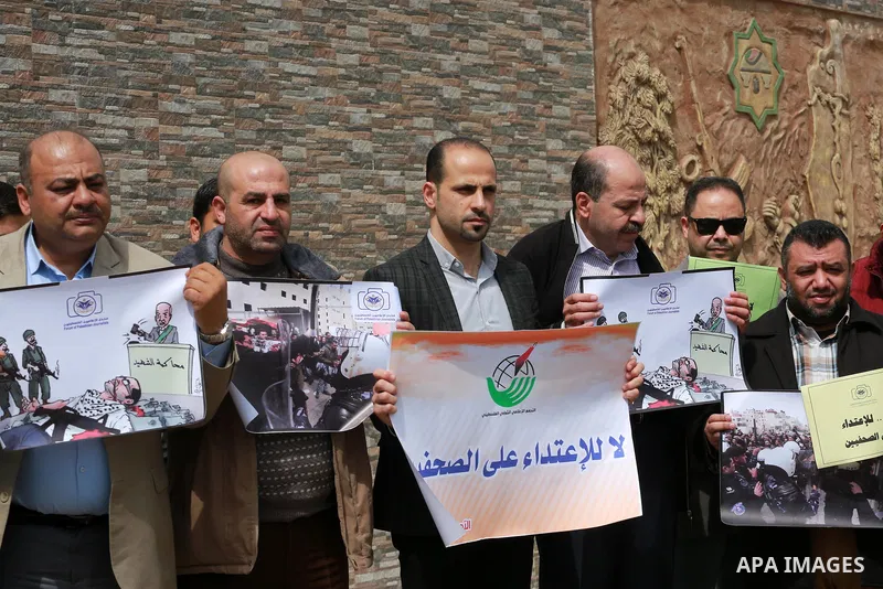 Palestinian journalists hold placards during a protest to show solidarity with their colleges in the West Bank, in front of the Legislative Council, in Gaza city on March 13, 2017. Photo by Mohammed Asad