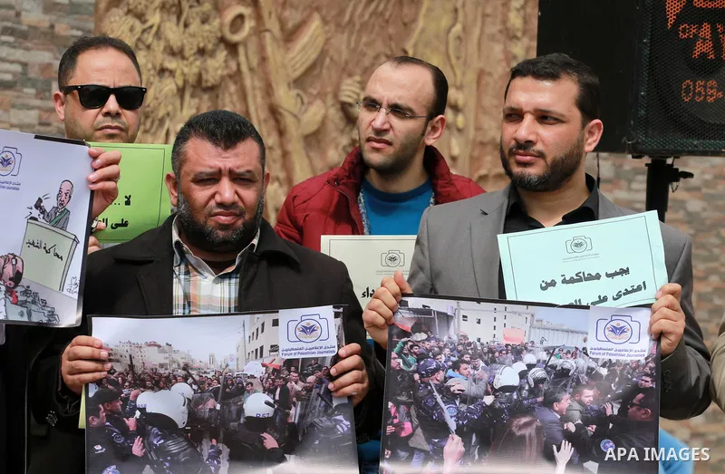 Palestinian journalists hold placards during a protest to show solidarity with their colleges in the West Bank, in front of the Legislative Council, in Gaza city on March 13, 2017. Photo by Mohammed Asad