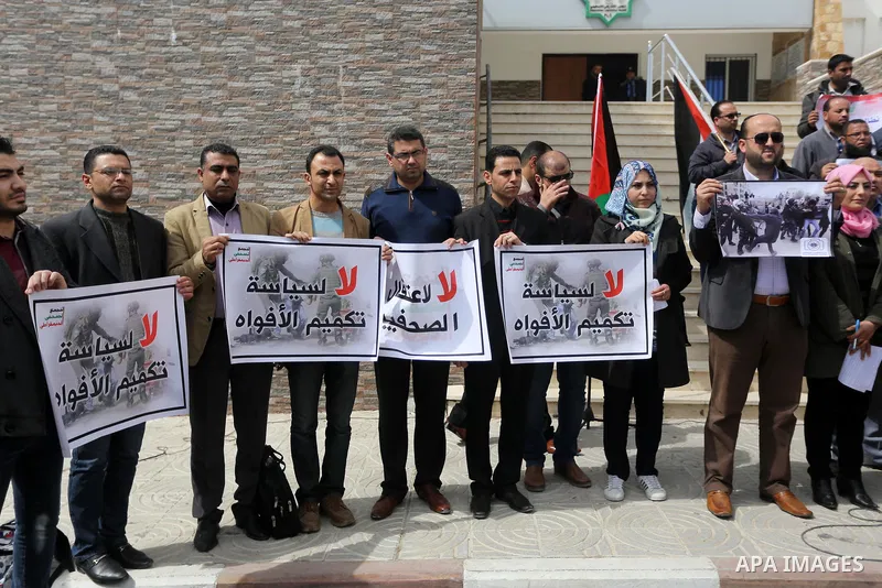 Palestinian journalists hold placards during a protest to show solidarity with their colleges in the West Bank, in front of the Legislative Council, in Gaza city on March 13, 2017. Photo by Mohammed Asad