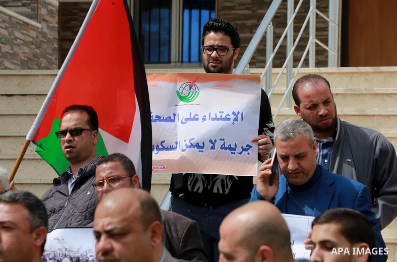 Palestinian journalists hold placards during a protest to show solidarity with their colleges in the West Bank, in front of the Legislative Council, in Gaza city on March 13, 2017. Photo by Mohammed Asad