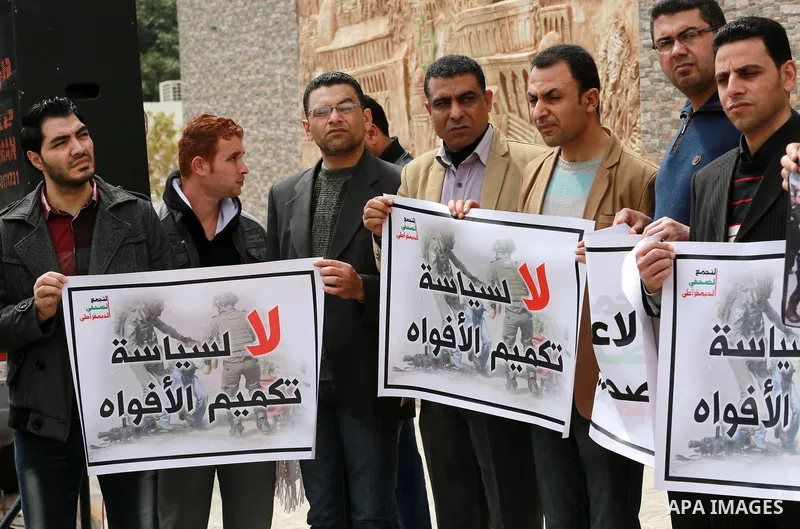 Palestinian journalists hold placards during a protest to show solidarity with their colleges in the West Bank, in front of the Legislative Council, in Gaza city on March 13, 2017. Photo by Mohammed Asad