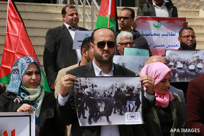 Palestinian journalists hold placards during a protest to show solidarity with their colleges in the West Bank, in front of the Legislative Council, in Gaza city on March 13, 2017. Photo by Mohammed Asad