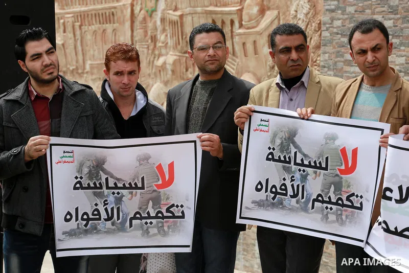 Palestinian journalists hold placards during a protest to show solidarity with their colleges in the West Bank, in front of the Legislative Council, in Gaza city on March 13, 2017. Photo by Mohammed Asad