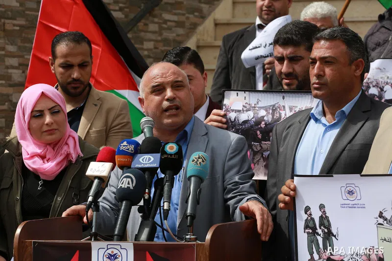 Palestinian journalists hold placards during a protest to show solidarity with their colleges in the West Bank, in front of the Legislative Council, in Gaza city on March 13, 2017. Photo by Mohammed Asad