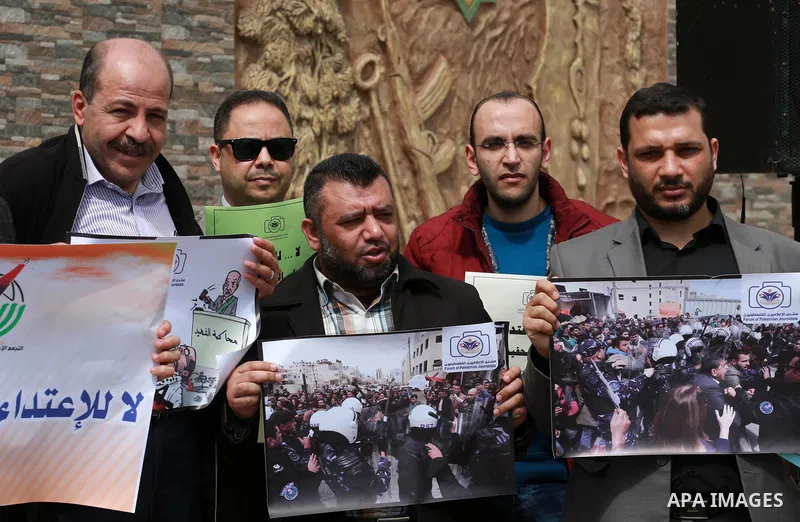 Palestinian journalists hold placards during a protest to show solidarity with their colleges in the West Bank, in front of the Legislative Council, in Gaza city on March 13, 2017. Photo by Mohammed Asad