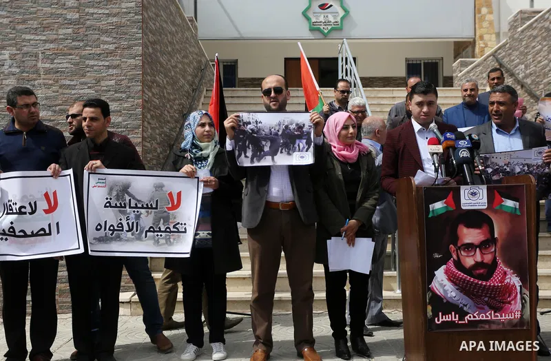 Palestinian journalists hold placards during a protest to show solidarity with their colleges in the West Bank, in front of the Legislative Council, in Gaza city on March 13, 2017. Photo by Mohammed Asad
