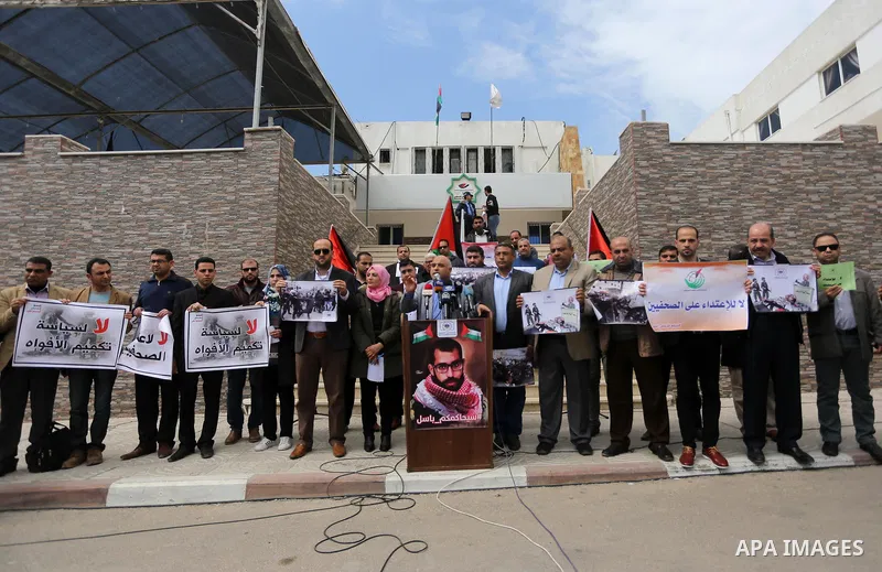 Palestinian journalists hold placards during a protest to show solidarity with their colleges in the West Bank, in front of the Legislative Council, in Gaza city on March 13, 2017. Photo by Mohammed Asad