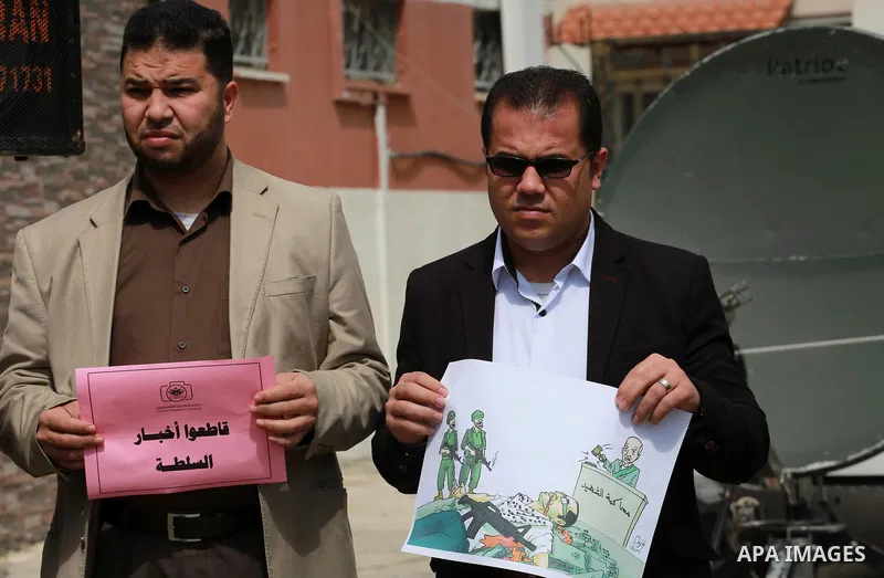 Palestinian journalists hold placards during a protest to show solidarity with their colleges in the West Bank, in front of the Legislative Council, in Gaza city on March 13, 2017. Photo by Mohammed Asad