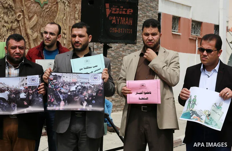 Palestinian journalists hold placards during a protest to show solidarity with their colleges in the West Bank, in front of the Legislative Council, in Gaza city on March 13, 2017. Photo by Mohammed Asad
