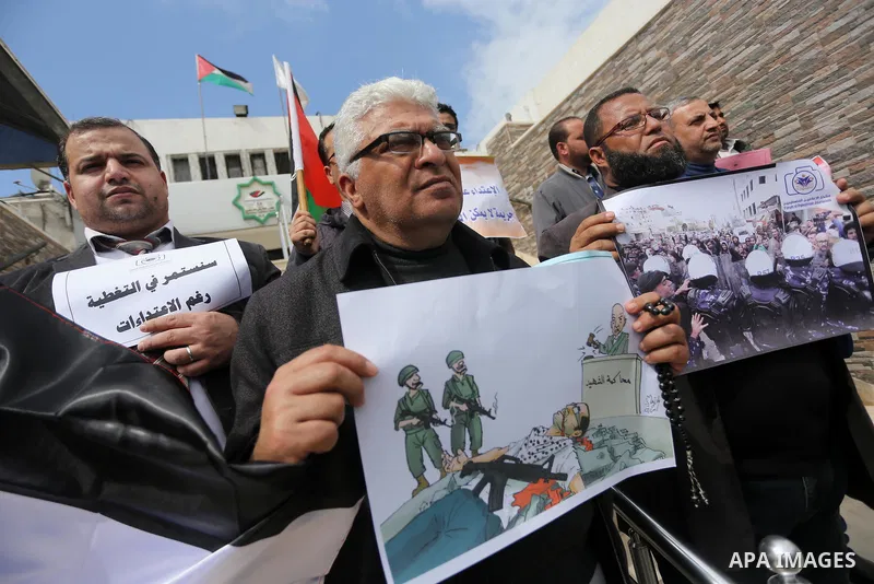Palestinian journalists hold placards during a protest to show solidarity with their colleges in the West Bank, in front of the Legislative Council, in Gaza city on March 13, 2017. Photo by Mohammed Asad