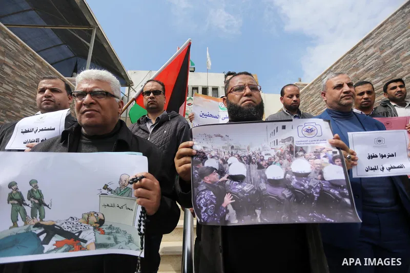 Palestinian journalists hold placards during a protest to show solidarity with their colleges in the West Bank, in front of the Legislative Council, in Gaza city on March 13, 2017. Photo by Mohammed Asad