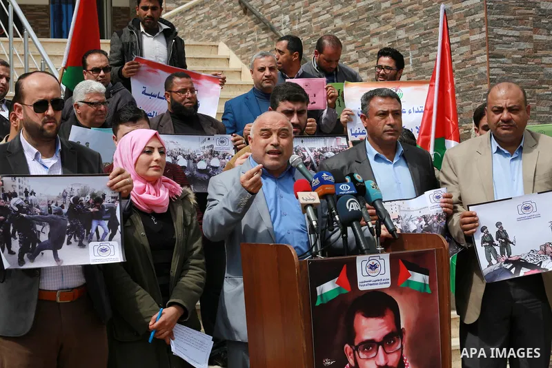 Palestinian journalists hold placards during a protest to show solidarity with their colleges in the West Bank, in front of the Legislative Council, in Gaza city on March 13, 2017. Photo by Mohammed Asad
