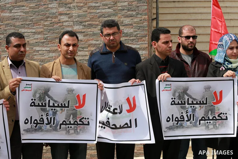 Palestinian journalists hold placards during a protest to show solidarity with their colleges in the West Bank, in front of the Legislative Council, in Gaza city on March 13, 2017. Photo by Mohammed Asad