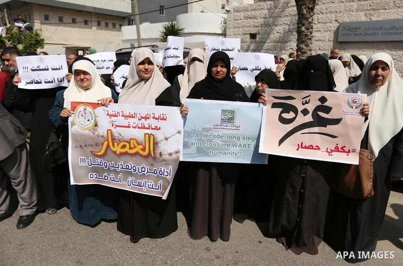 Palestinians hold placards during a protest calling for end the Israeli blockade on Gaza Strip, outside the UN offices, in Gaza city, on March 13, 2017. Photo by Ashraf Amra