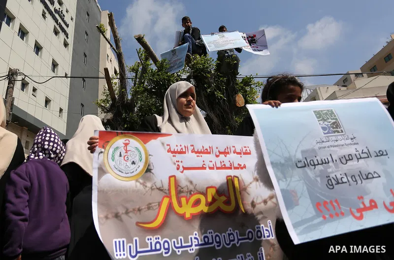 Palestinians hold placards during a protest calling for end the Israeli blockade on Gaza Strip, outside the UN offices, in Gaza city, on March 13, 2017. Photo by Ashraf Amra