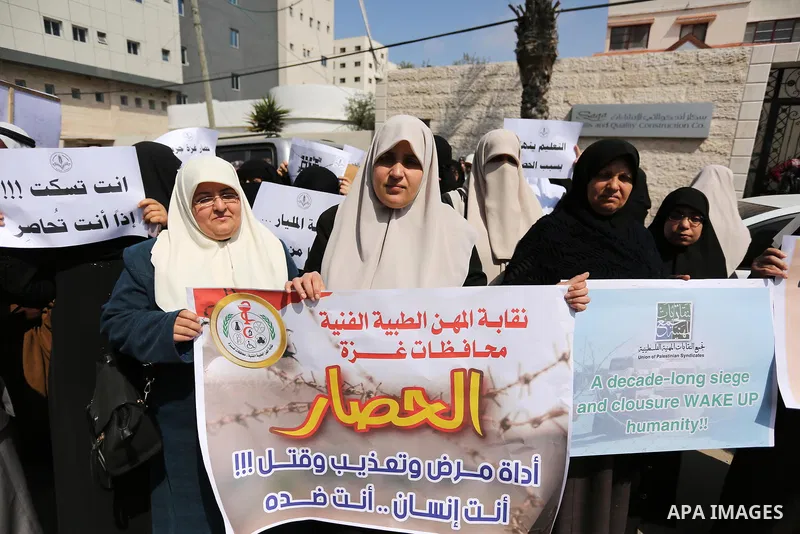 Palestinians hold placards during a protest calling for end the Israeli blockade on Gaza Strip, outside the UN offices, in Gaza city, on March 13, 2017. Photo by Ashraf Amra