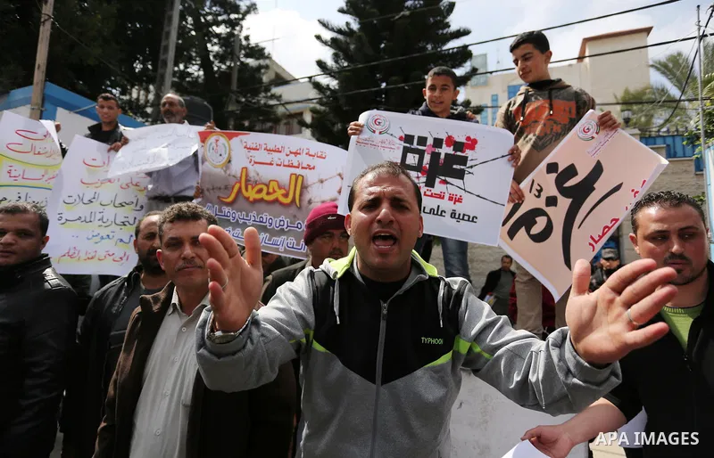 Palestinians hold placards during a protest calling for end the Israeli blockade on Gaza Strip, outside the UN offices, in Gaza city, on March 13, 2017. Photo by Ashraf Amra