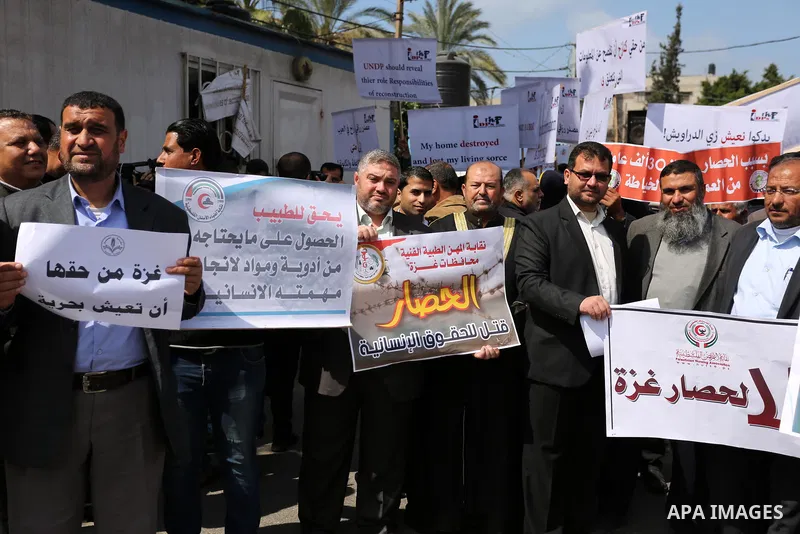 Palestinians hold placards during a protest calling for end the Israeli blockade on Gaza Strip, outside the UN offices, in Gaza city, on March 13, 2017. Photo by Ashraf Amra