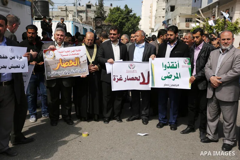 Palestinians hold placards during a protest calling for end the Israeli blockade on Gaza Strip, outside the UN offices, in Gaza city, on March 13, 2017. Photo by Ashraf Amra