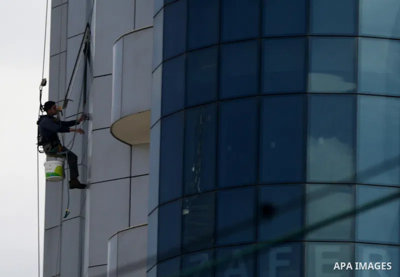 A Palestinian window cleaner hangs from ropes as he cleans windows of Al-zafer tower in Gaza City, in March 15, 2017. Photo by Yasser Qudih