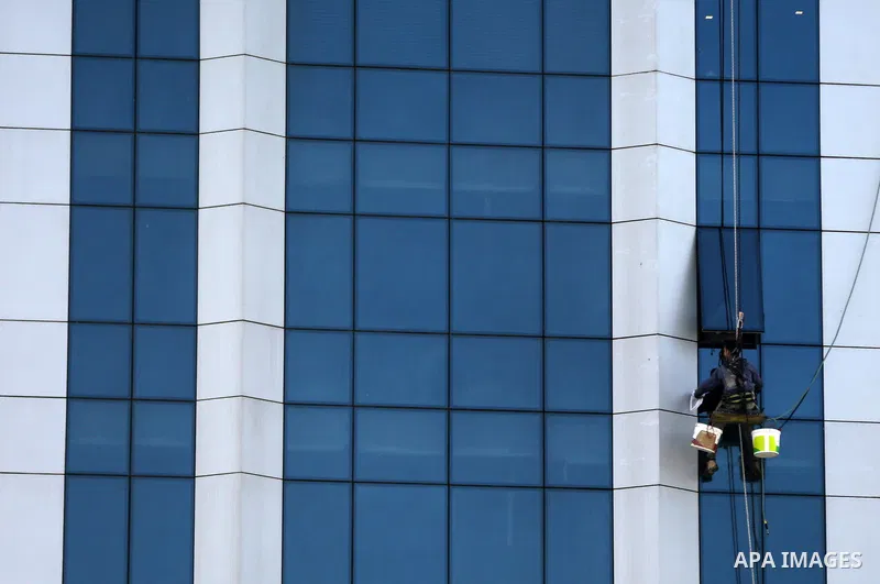 A Palestinian window cleaner hangs from ropes as he cleans windows of Al-zafer tower in Gaza City, in March 15, 2017. Photo by Yasser Qudih