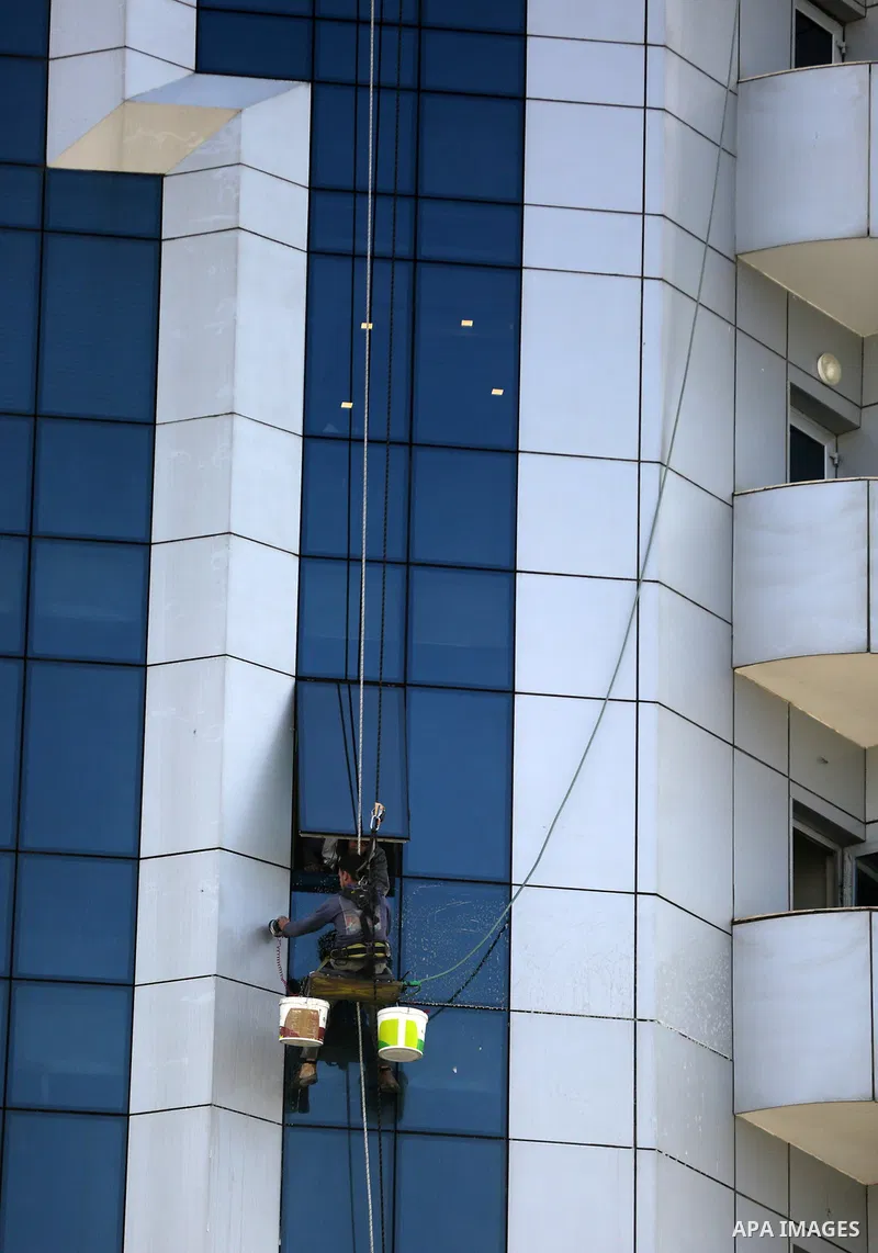A Palestinian window cleaner hangs from ropes as he cleans windows of Al-zafer tower in Gaza City, in March 15, 2017. Photo by Yasser Qudih
