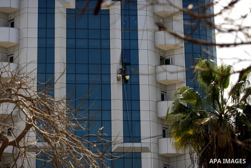 A Palestinian window cleaner hangs from ropes as he cleans windows of Al-zafer tower in Gaza City, in March 15, 2017. Photo by Yasser Qudih
